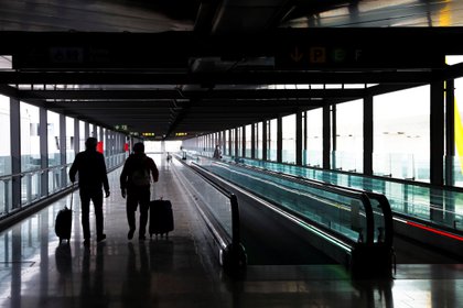 Dos pasajeros cruzan una de las terminales del Aeropuerto Adolfo Suárez Madrid-Baraja. EFE/Emilio Naranjo/Archivo

