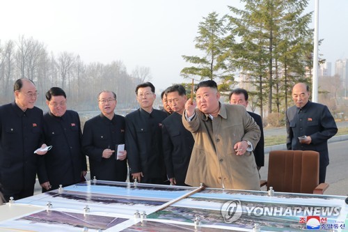 La foto, proporcionada por la KCNA, muestra al líder norcoreano, Kim Jong-un (dcha., frente), inspeccionando, el 25 de marzo de 2021, un sitio donde se construirán casas adosadas cerca del río, alrededor de la puerta Pothong, en Pyongyang. Kim no supervisó el lanzamiento de un nuevo tipo de misil que el Norte llevó a cabo el mismo día. (Uso exclusivo dentro de Corea del Sur. Prohibida su distribución parcial o total)