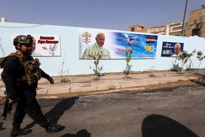 Un policía iraquí patrulla por una calle de Bagadad con carteles y murales alusivos a la visita del papa Francisco.EFE/EPA/AHMED JALIL
