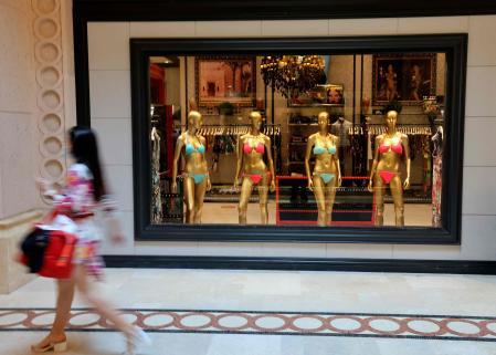 A Mask-clad woman walks past a luxury shop displaying bikinis, on the man-made archipelago of Palm Jumeira, in the Gulf Emirate of Dubai, on February 24, 2021. (Photo by Karim SAHIB / AFP)