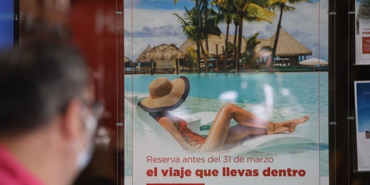 Un hombre pasa frente al escaparate de una agencia de viajes.