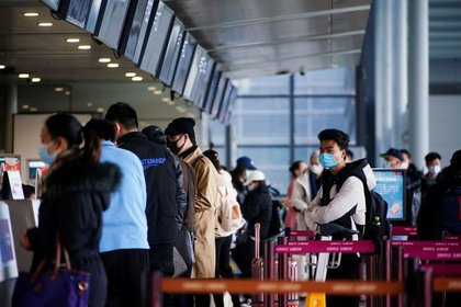 Viajeros con mascarillas durante la epidemia de coronavirus (COVID-19) hacen cola en los mostradores de facturación del aeropuerto internacional de Shanghái Hongqiao, en Shanghái, China, 28 de enero de 2021. REUTERS/Aly Song
