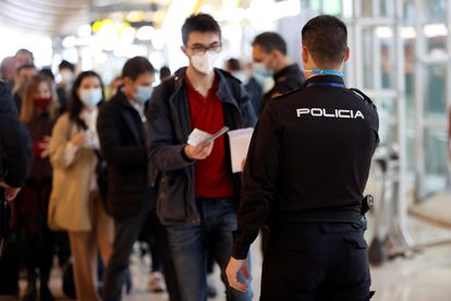 Un policía controla el paso de viajeros en el aeropuerto de Madrid, el pasado viernes.