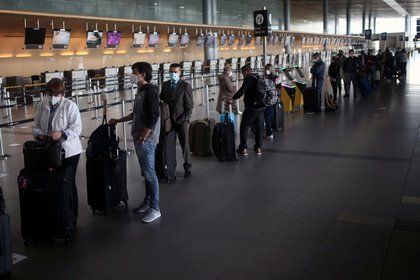 Pasajeros utilizando mascarillas hacen fila para realizar el check-in en el aeropuerto El Dorado, después de que el Gobierno colombiano autorizó la reactivación de los vuelos internacionales, en medio del brote de coronavirus en Bogotá. Septiembre 21, 2020. REUTERS/Luisa Gonzalez