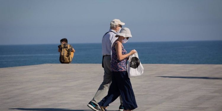 Dos personas protegidas con mascarillas pasean por el Paseo Marítimo de la Playa de la Barceloneta, en Barcelona/Catalunya