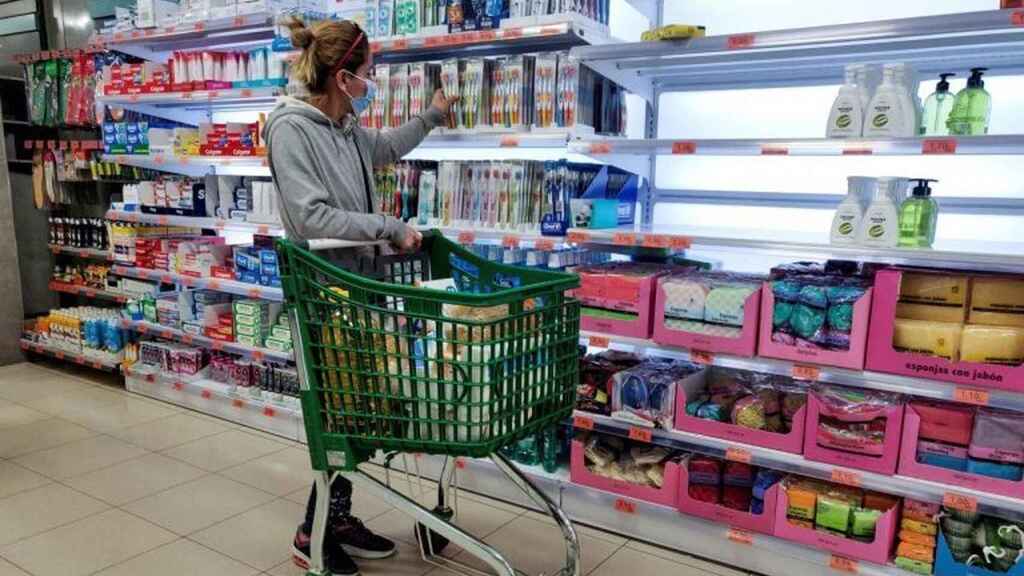 Una consumidora, en un supermercado, eligiendo un producto para su cesta de la compra.