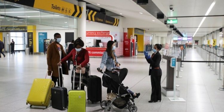 Passengers wearing face masks wait in front of the check-in counters at Gatwick Airport, amid the coronavirus disease (COVID-19) outbreak, in Gatwick, Britain June 15, 2020. REUTERS/Peter Cziborra