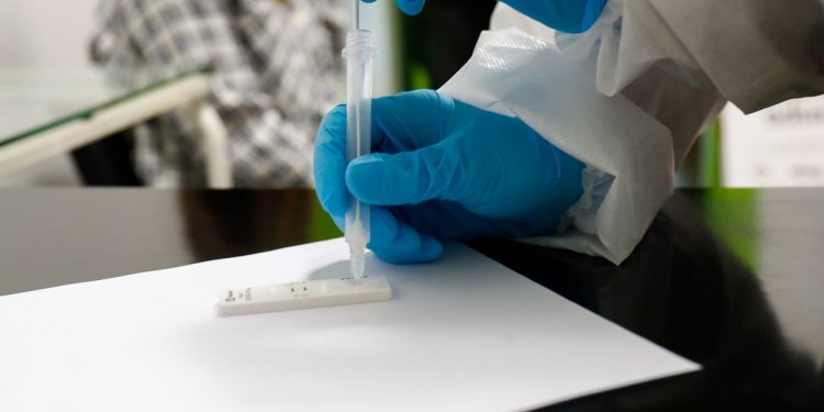 Una trabajadora sanitaria sostiene un test de antígenos.