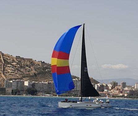 Una de las embarcaciones de la regata con la ciudad y el castillo al fondo