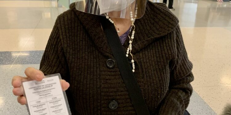 María Gloria Partida, 74, muestra su certificado de vacunación contra covid-19 que tuvo que mostrar antes de subir al avión, en México.