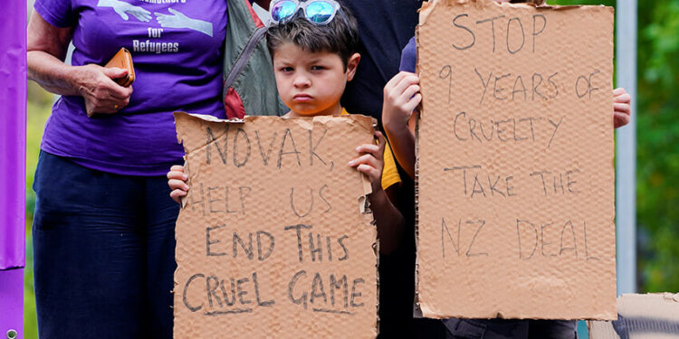 Unos niños sostienen carteles en los que piden al tenista serbio Novak Djokovic que apoye a las personas refugiadas que están retenidas en el Park Hotel