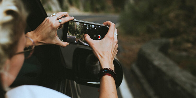Mujer tomando video con un móvil desde la ventana del auto