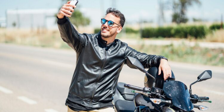 hombre con motocicleta tomando selfie con iphone chaqueta de cuero