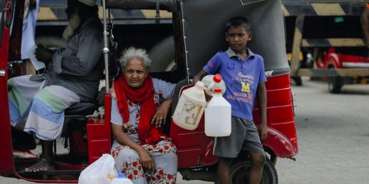 Un niño sostiene contenedores vacíos mientras espera con los miembros de su familia para comprar aceite de queroseno para cocinas de queroseno en medio de la escasez de gas doméstico en Sri Lanka.