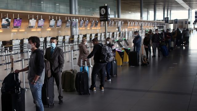 Pasajeros utilizando mascarillas hacen fila para realizar el check-in en el aeropuerto El Dorado. REUTERS/Luisa Gonzalez