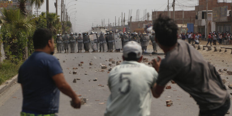 Riot police confront demonstrators during clashes which erupted in the framework of a partial strike of cargo and passenger carriers, in Ate, a district east of Lima, on April 4, 2022. - A partial strike of cargo and passenger carriers caused road blockades and suspension of classes in Peru, in the first strike against the government of leftist President Pedro Castillo. (Photo by Gian MASKO / AFP)