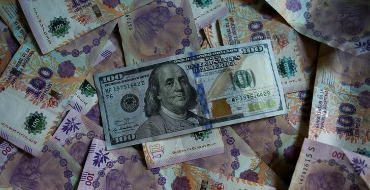 IMAGEN DE ARCHIVO. Billetes de 100 pesos argentinos debajo de un billete de 100 dólares en esta ilustración tomada el 3 de septiembre de 2019. REUTERS/Agustin Marcarian/Ilustración