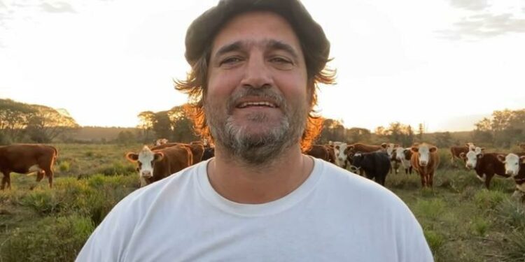 El productor Alejandro de Tezanos Pinto en su establecimiento ganadero en Entre Ríos, detrás su rodeo de vacas de cría