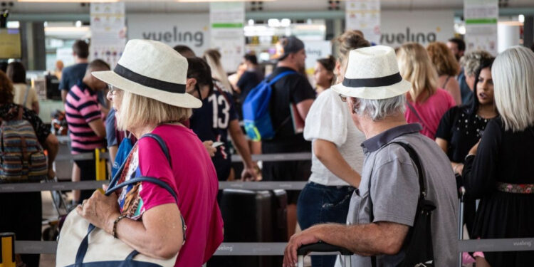 Diferentes viajeros esperan en el aeropuerto para subir a una avión de Vueling / EP
