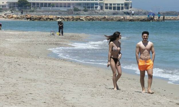 Dos jóvenes pasean por la playa de las Sirenas, en La Manga