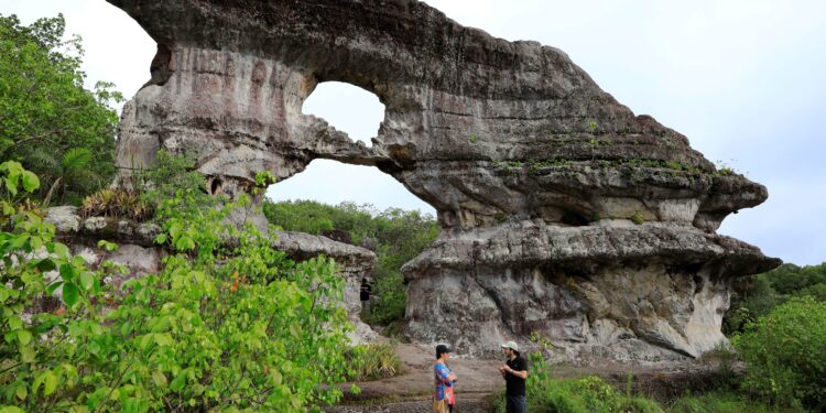 Fotografía del 30 de septiembre de 2021 que muestra a un grupo de visitantes que recorre la Puerta de Orión, una formación rocosa en zona rural de San José de Guaviare (Colombia). EFE/Carlos Ortega

