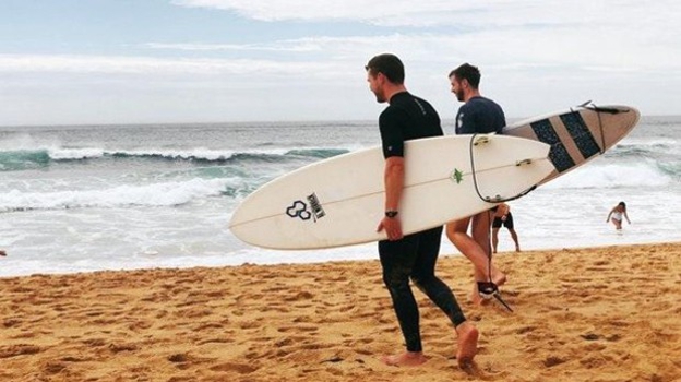 Jóvenes dirigiéndose al agua para surfear