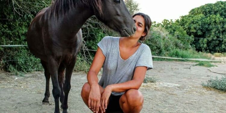 Chica besando a un caballo en zona rural