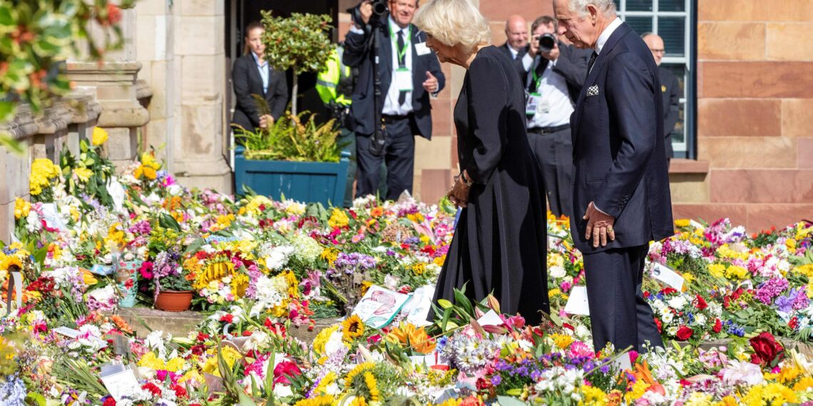 El rey británico Carlos III y la reina consorte Camilla miran las flores y los homenajes a su llegada al castillo de Hillsborough, en Belfast, el 13 de septiembre de 2022, durante una visita a Irlanda del Norte
