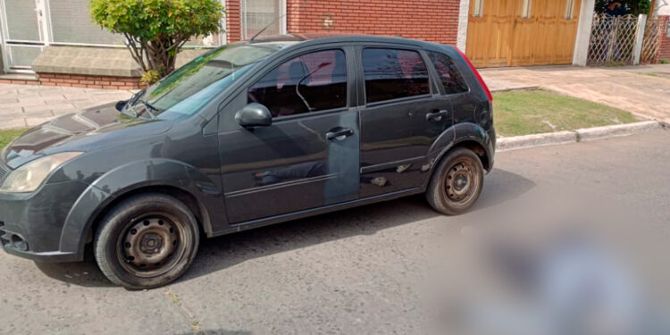 El auto del policía y su cuñado y, a un costado, el ladrón abatido