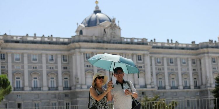 FOTO DE ARCHIVO. Turistas se resguardan del sol bajo una sombrilla cerca del Palacio Real durante un día caluroso con temperaturas que alcanzan los 37 grados centígrados en Madrid, España. 9 de agosto de 2022. REUTERS/Isabel Infantes