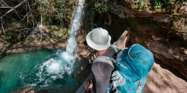 Viajero con mochila observando una cascada desde mirador