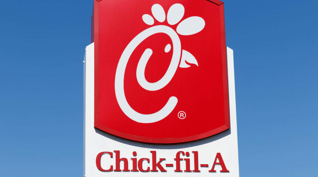 Primer plano de la señalización de Chick-fil-A contra un cielo azul.