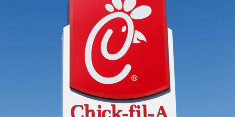 Primer plano de la señalización de Chick-fil-A contra un cielo azul.