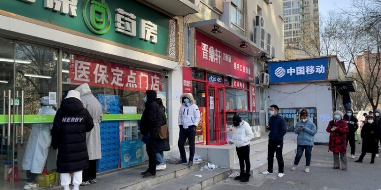 Personas con mascarillas hacen cola frente a una farmacia para comprar productos mientras continúan los brotes de la enfermedad por coronavirus (COVID-19) en Pekín, China, el 6 de diciembre de 2022. REUTERS/Alessandro Diviggiano
