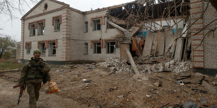Un militar ucraniano pasa por delante de un edificio dañado durante un ataque con misiles rusos en el pueblo de Novooleksandrivka, en la región de Kherson, Ucrania