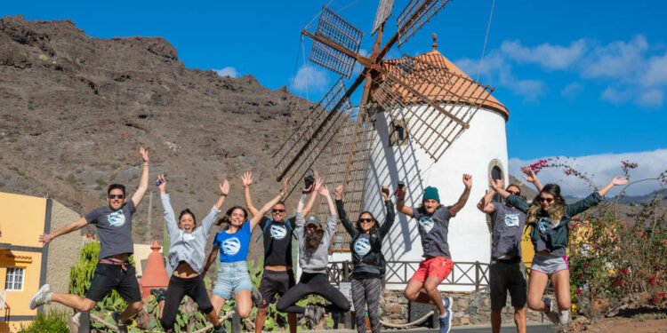 Grupo de jóvenes saltando en zona rural delante de un molino 