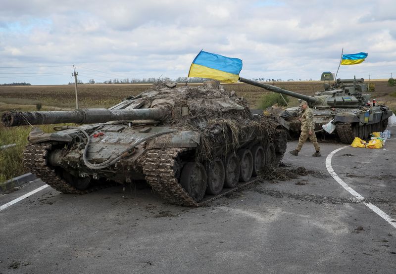 Un militar ucraniano camina cerca de tanques rusos capturados con banderas ucranianas puestas sobre ellos, mientras continúa el ataque de Rusia a Ucrania