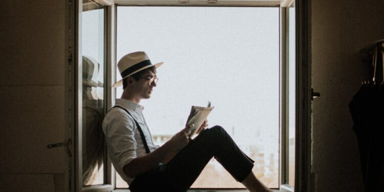 Hombre leyendo un libro en la ventana.