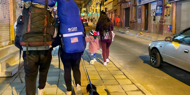 Al caer la noche, los caminantes llegan a Tulcan después de viajar durante días cargando sus pertenencias a la espalda.