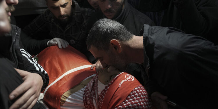 Dolientes asisten al funeral del palestino Omar Khumour, de 14 años, en Belén, Cisjordania, el lunes 16 de enero de 2022. El chico murió de un disparo en la cabeza durante una operación militar israelí en el campamento de refugiados de Dheisha, próxima a la ciudad de Belén. (AP Foto/Mahmoud Illean)