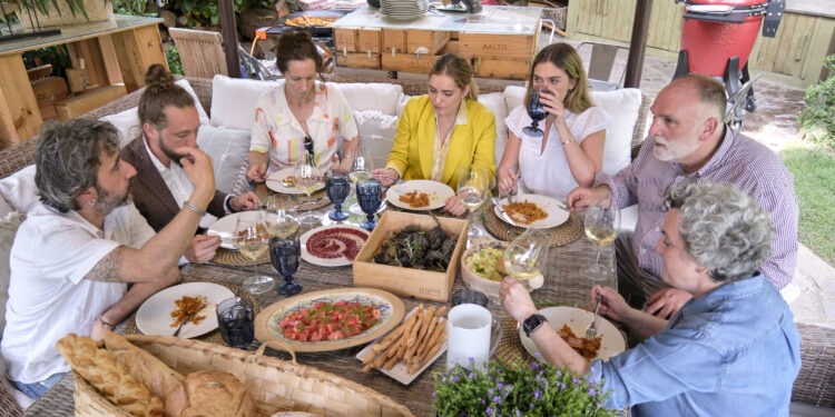 En esta imagen proporcionada por Discovery, Diego Guerrero, de izquierda a derecha, Carlos Sánchez, Mila, Inés Andrés, Carlota Andrés, José Andrés y Pepa Muñoz disfrutan de una comida preparada por los chefs en la casa de Muñoz en una escena de la serie de Discovery + "Jose Andres and Family in Spain" (“Chef José Andrés y familia”). (Xaume Olleros/Discovery vía AP)