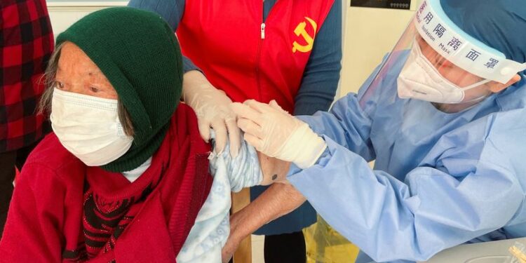FILE PHOTO: A medical worker administers a dose of a vaccine against coronavirus disease (COVID-19) to an elderly resident, during a government-organized visit to a vaccination center in Zhongmin village on the outskirts of Shanghai, China December 21, 2022. REUTERS/Brenda Goh
