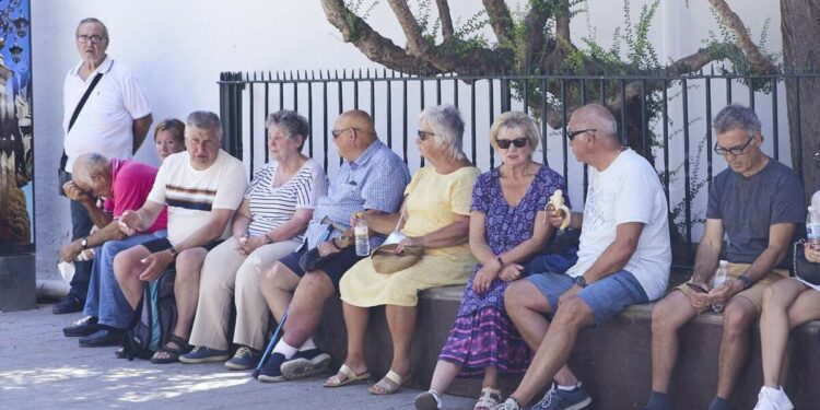 Personas mayores sentadas y comiendo en la sombra