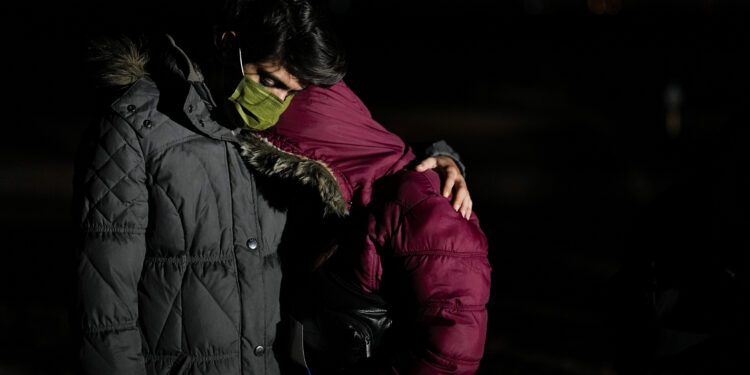 El migrante cubano Mario Pérez abraza a su esposa mientras esperan solicitar asilo luego de cruzar la frontera a Estados Unidos, el viernes 6 de enero de 2023, cerca de Yuma, Arizona. (AP Foto/Gregory Bull)