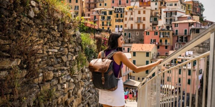 Chica con mochila paseando por Cinque Terre, Italia