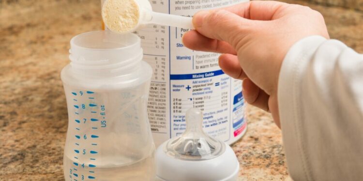 Mother prepares baby formula in kitchen