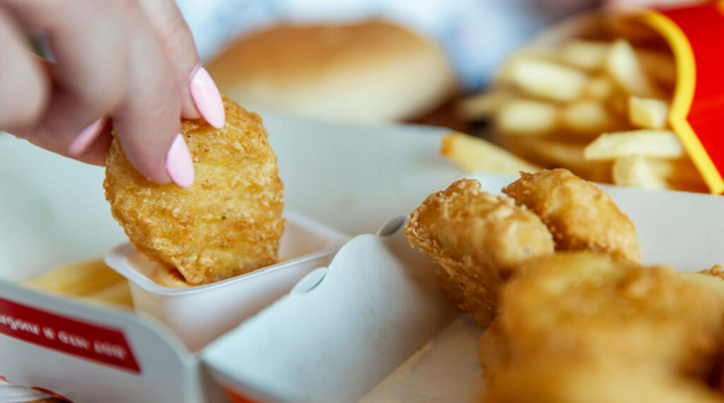 A woman eats Chicken Nuggets at McDonalds. Close-up.