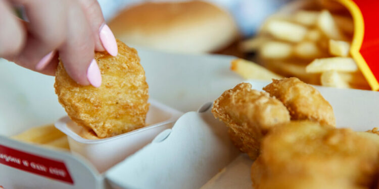 A woman eats Chicken Nuggets at McDonalds. Close-up.