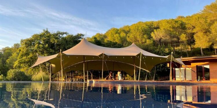 Gran carpa beduina junto a una piscina con el reflejo en el agua