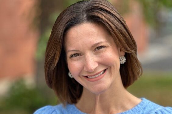 A woman smiles while posing for a headshot outside.